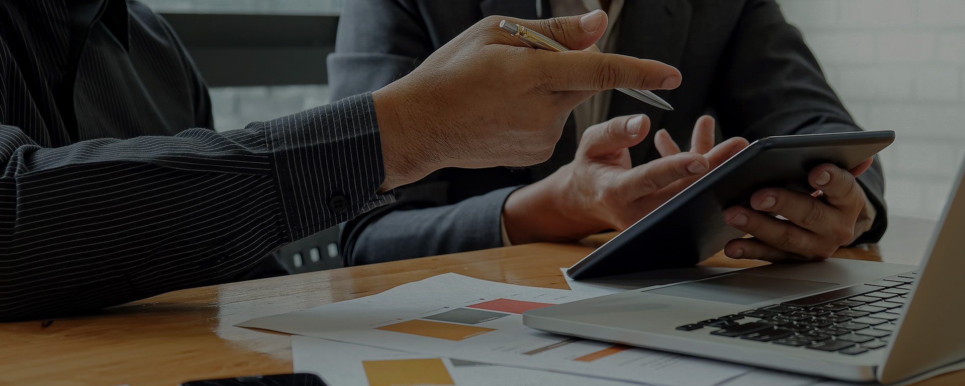 Close up of two people discussing price optimisation and pointing to competitive pricing strategy results shown on laptop screen 